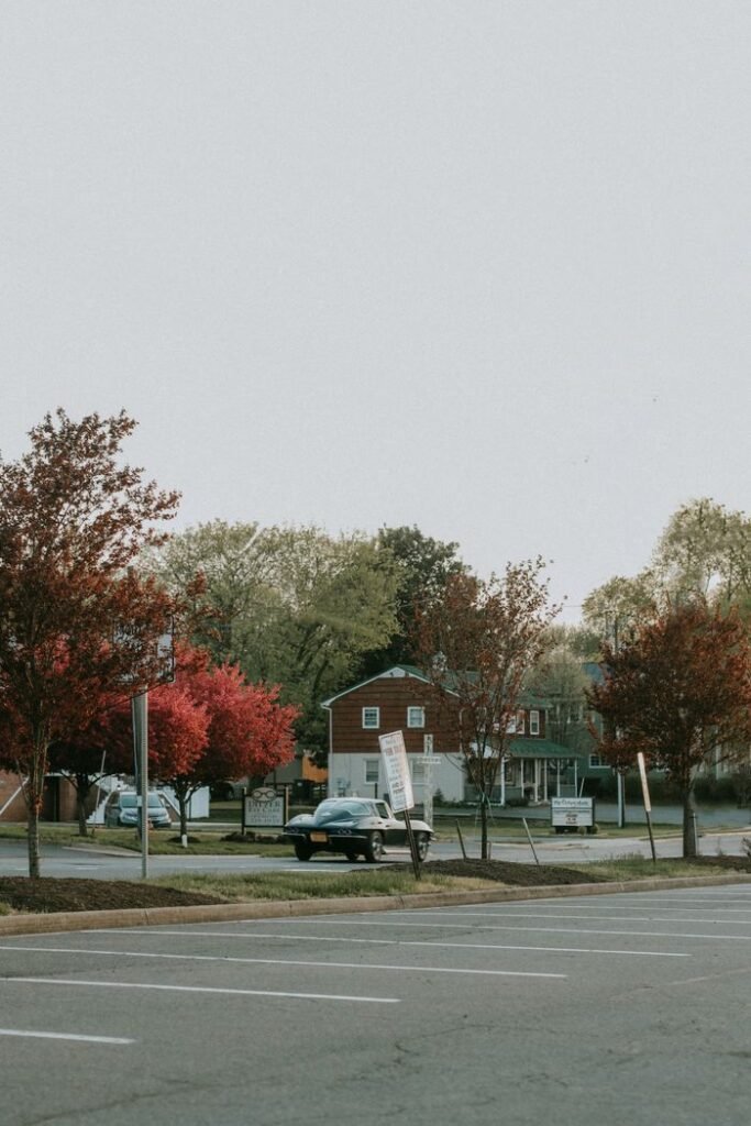 A quiet street scene with vintage car and colorful autumn trees, showcasing suburban charm.