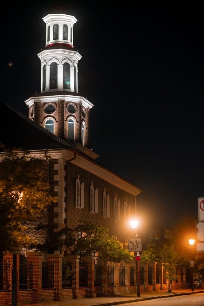 A beautifully lit historical church tower in Alexandria, Virginia against the night sky.